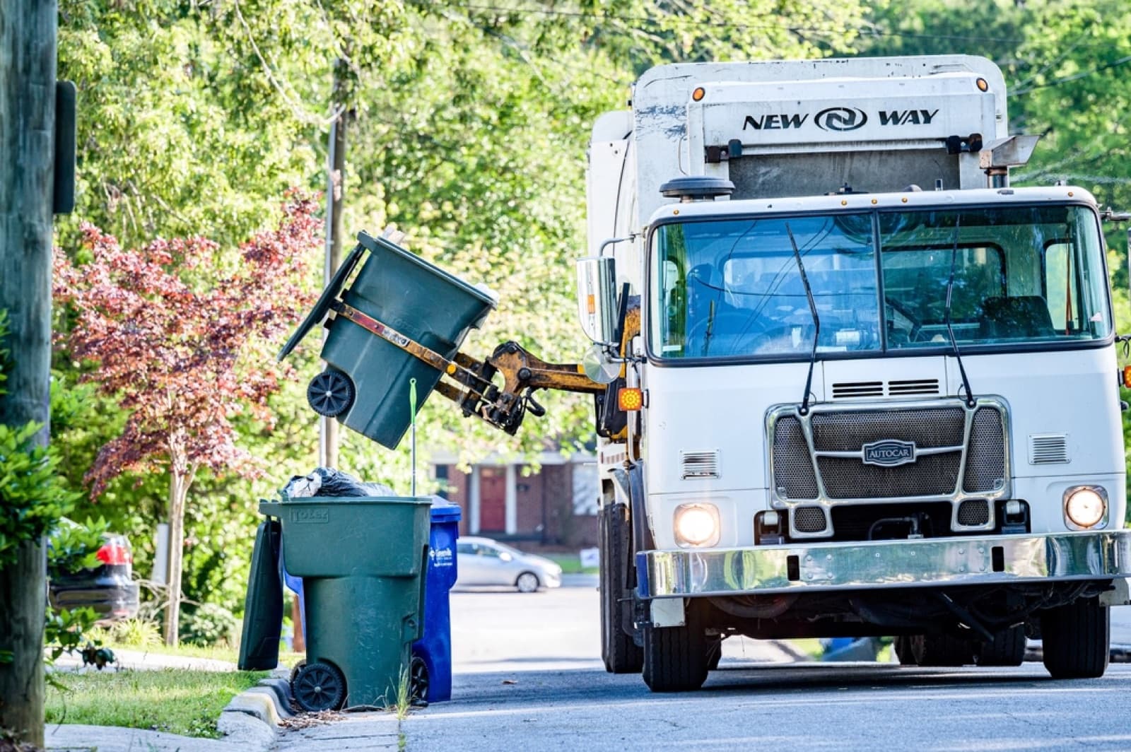 Residential garbage and organics carts lined up at a suburban curb on collection day