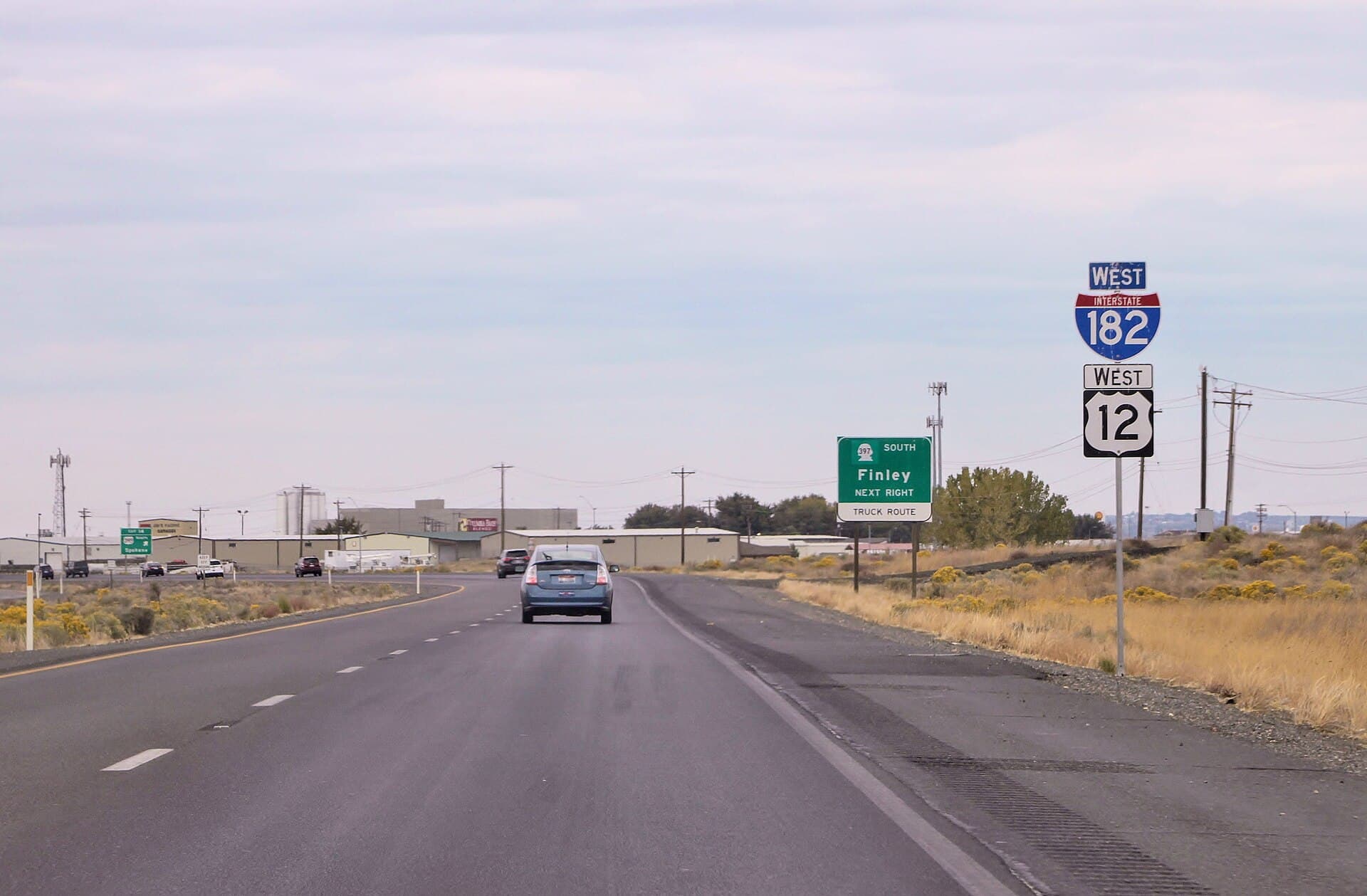 A highway on an exposed ridge obscured by a wall of blowing dust, similar to conditions on SR 397 south of Kennewick