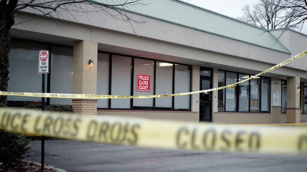 A closed storefront with blinds drawn and police tape, representing a shuttered Kennewick massage business
