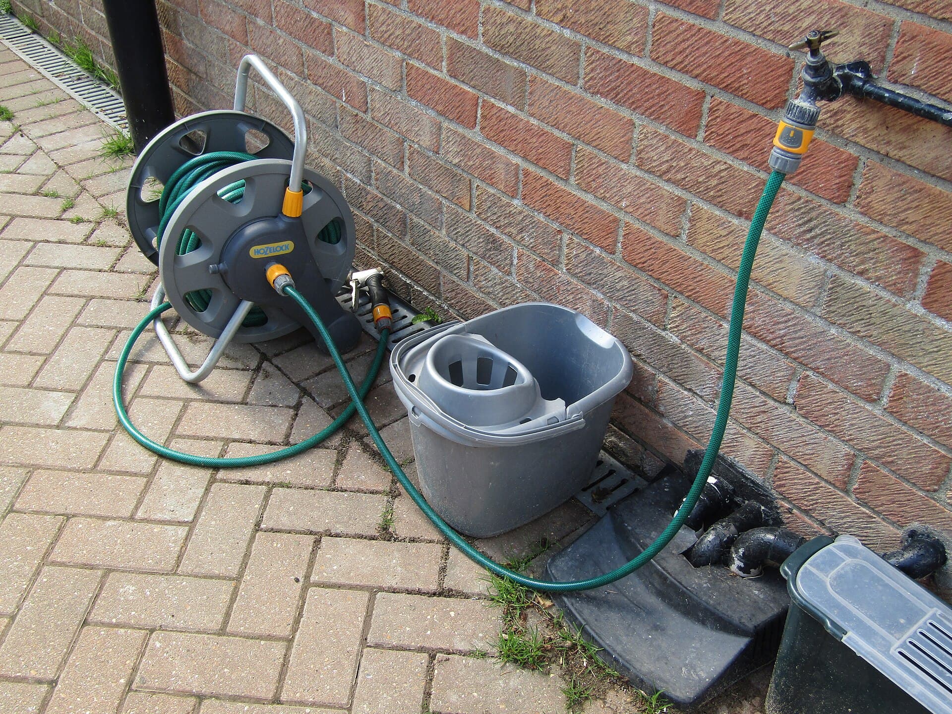 Frost forming on an outdoor hose bib and coiled garden hose on a suburban house exterior